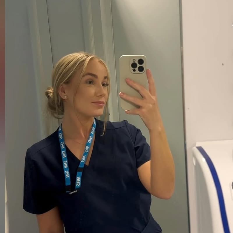 Nursing student in navy scrubs wearing a hospital lanyard