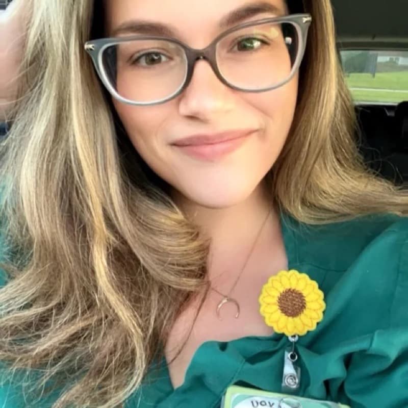 Nursing student in green scrubs smiling before a shift